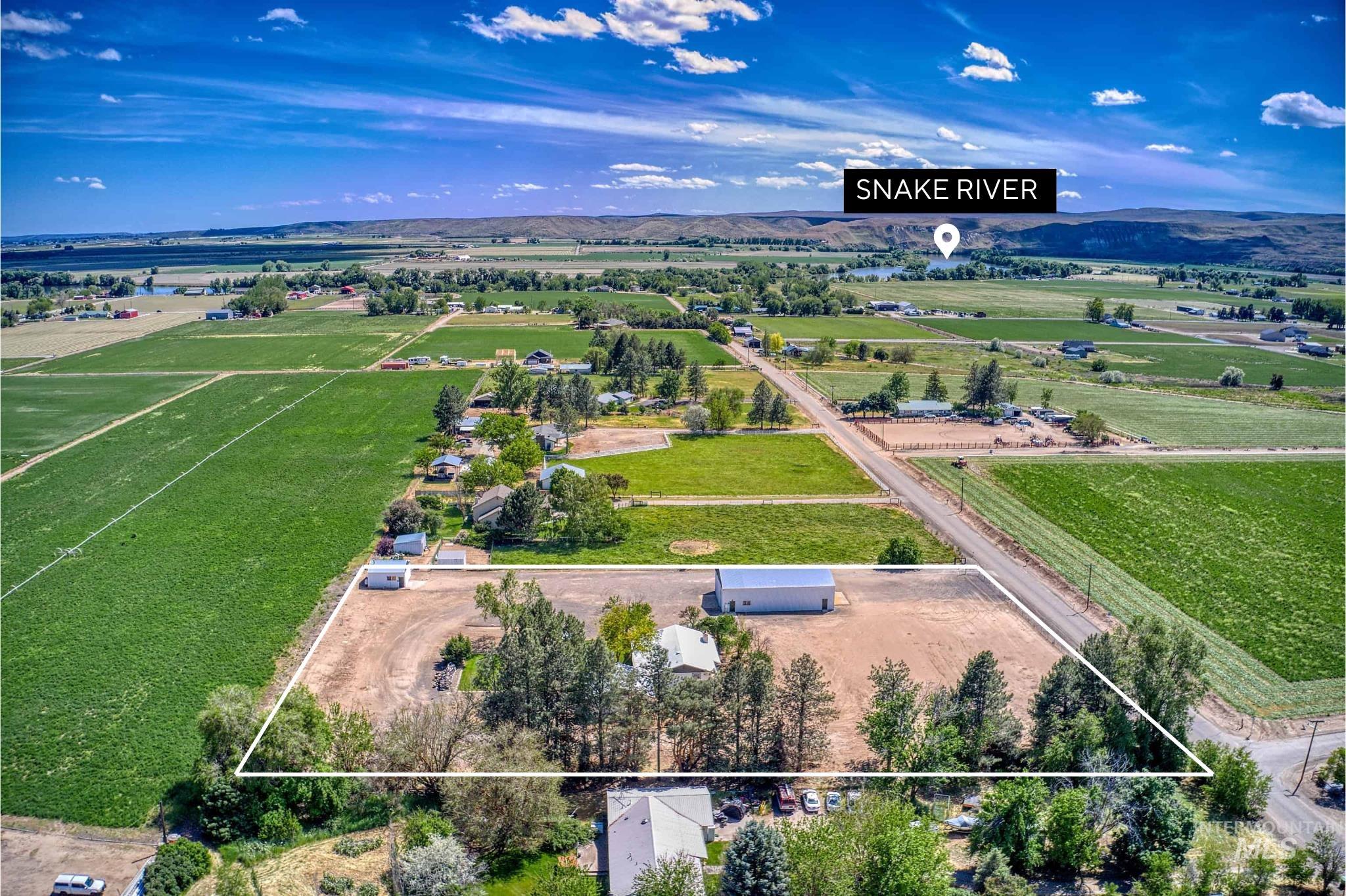748 Pringle Road Weiser, ID 83672 - Photo 44 of 47 Expansive rural property featuring a large white outbuilding, mature trees, and a gravel driveway