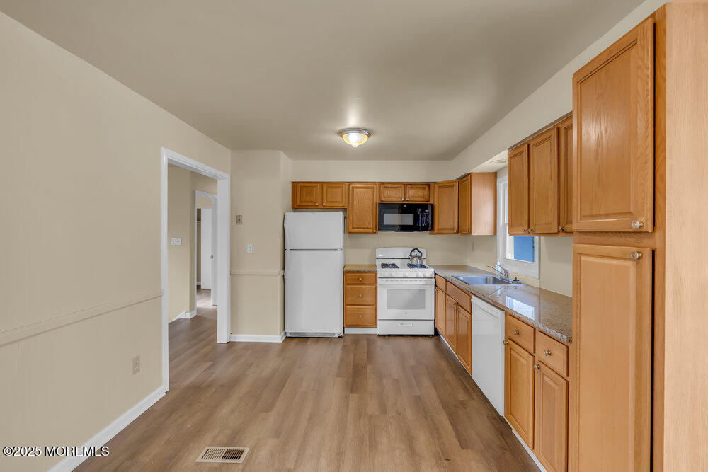 32 Pine Tree Drive Bayville, NJ 08721 - Photo 17 of 63 a kitchen with stainless steel appliances granite countertop a refrigerator a stove top oven a sink and dishwasher with wooden floor