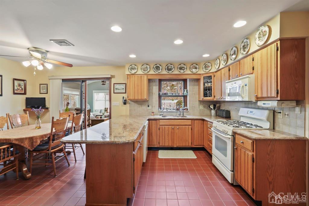10 Bennett Road Old Bridge, NJ 07747 - Photo 9 of 35 a kitchen with stainless steel appliances granite countertop a refrigerator a sink dishwasher a dining table and chairs with wooden floor