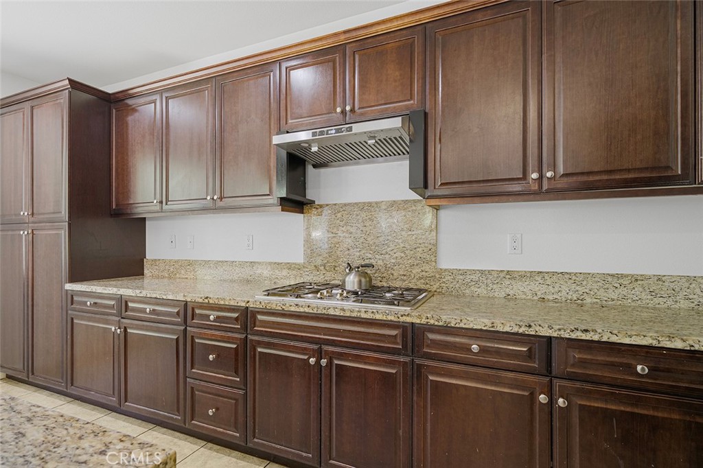 12936 Canopy Court Rancho Cucamonga, CA 91739 - Photo 10 of 30 a kitchen with granite countertop wooden cabinets and a stove top oven