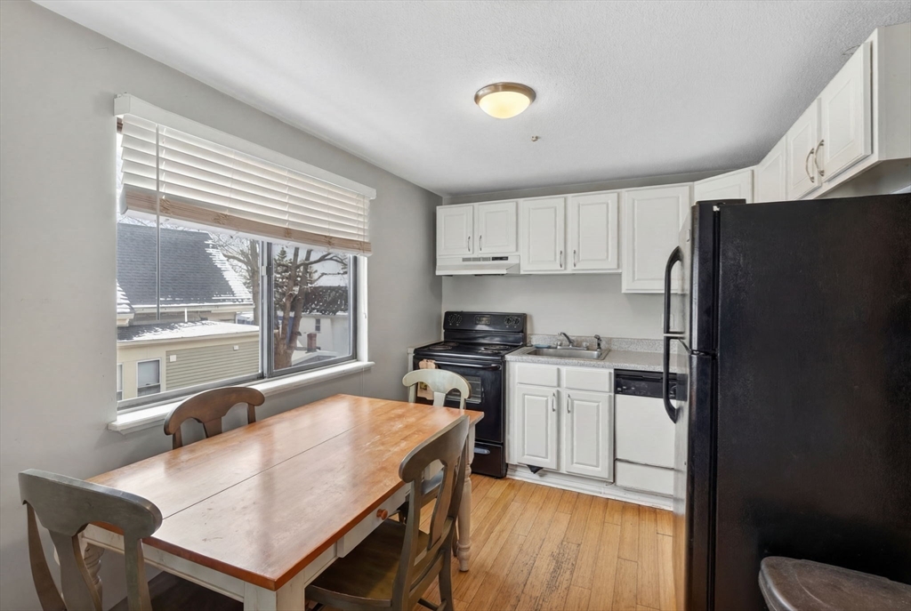10-16 Stephen Street, Unit 5 Lynn, MA 01902 - Photo 12 of 26 a kitchen with stainless steel appliances granite countertop a stove a refrigerator a sink a dining table and chairs with wooden floor