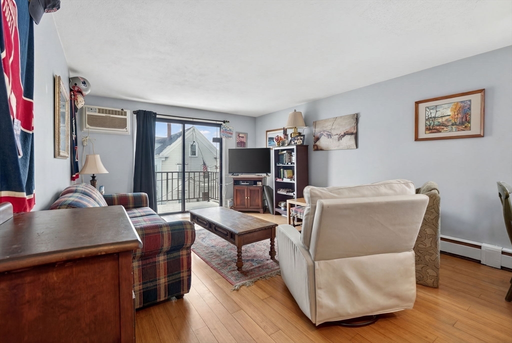 10-16 Stephen Street, Unit 5 Lynn, MA 01902 - Photo 8 of 26 a living room with furniture a flat screen tv and a floor to ceiling window