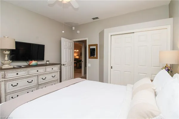 a bedroom with a bed and a flat screen tv in white dresser