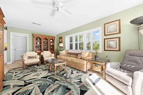 a living room with furniture large windows and wooden floor