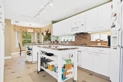 a kitchen with stainless steel appliances granite countertop a stove a sink dishwasher and white cabinets with wooden floor