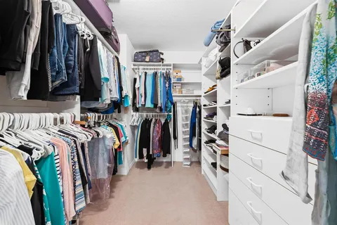 a view of walk in closet with clothes and shoes