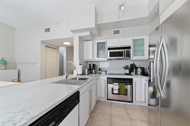 a kitchen with stainless steel appliances granite countertop a refrigerator a stove top oven a sink and dishwasher