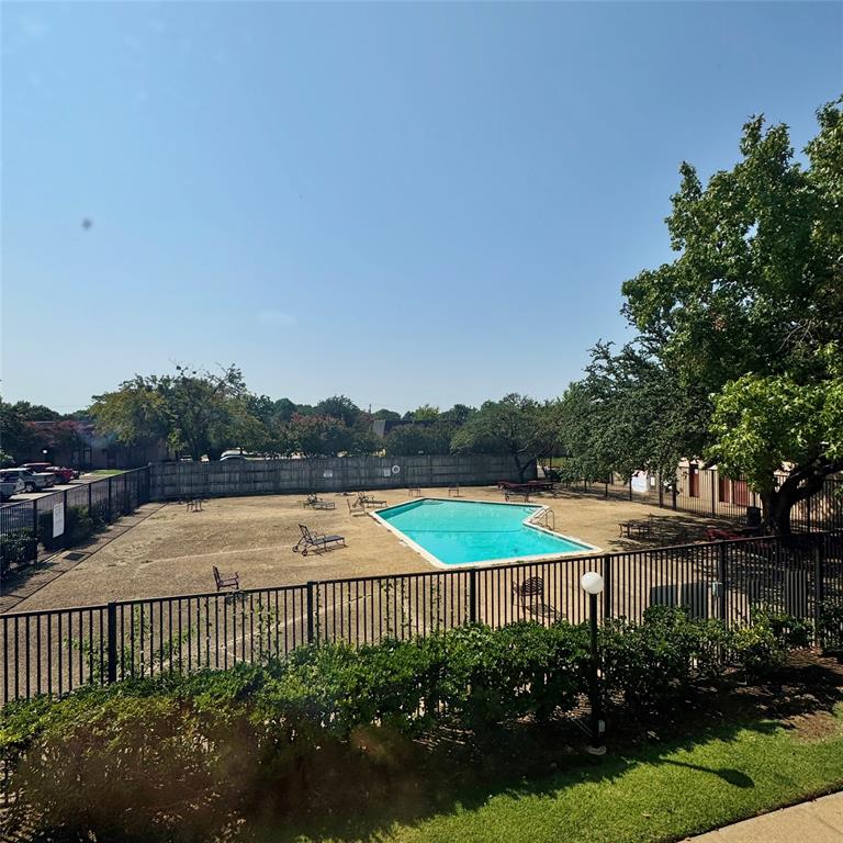 1809 East Grauwyler Road, Unit 133 Irving, TX 75061 - Photo 13 of 18 a view of a patio with a table and chairs under an umbrella with palm trees