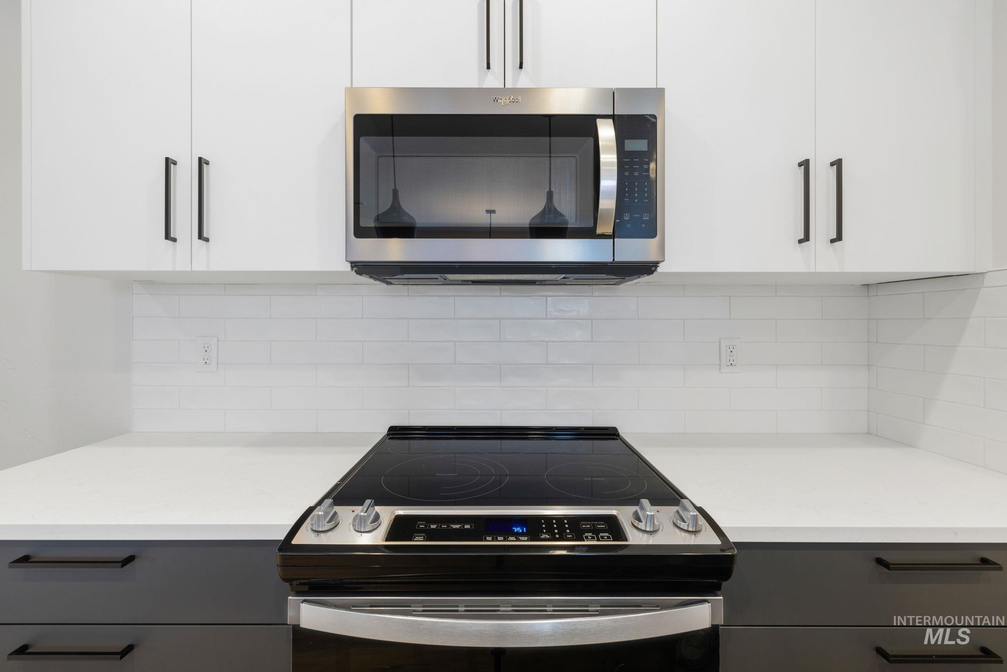 22 Bridger Street Cascade, ID 83611 - Photo 13 of 39 Kitchen with electric range, stainless steel microwave, white cabinetry, and tasteful backsplash