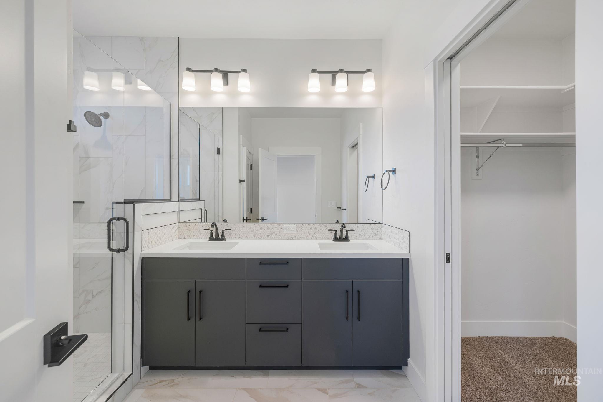 22 Bridger Street Cascade, ID 83611 - Photo 22 of 39 Bathroom with a marble finish shower, light marble finish flooring, double vanity, and a walk in closet
