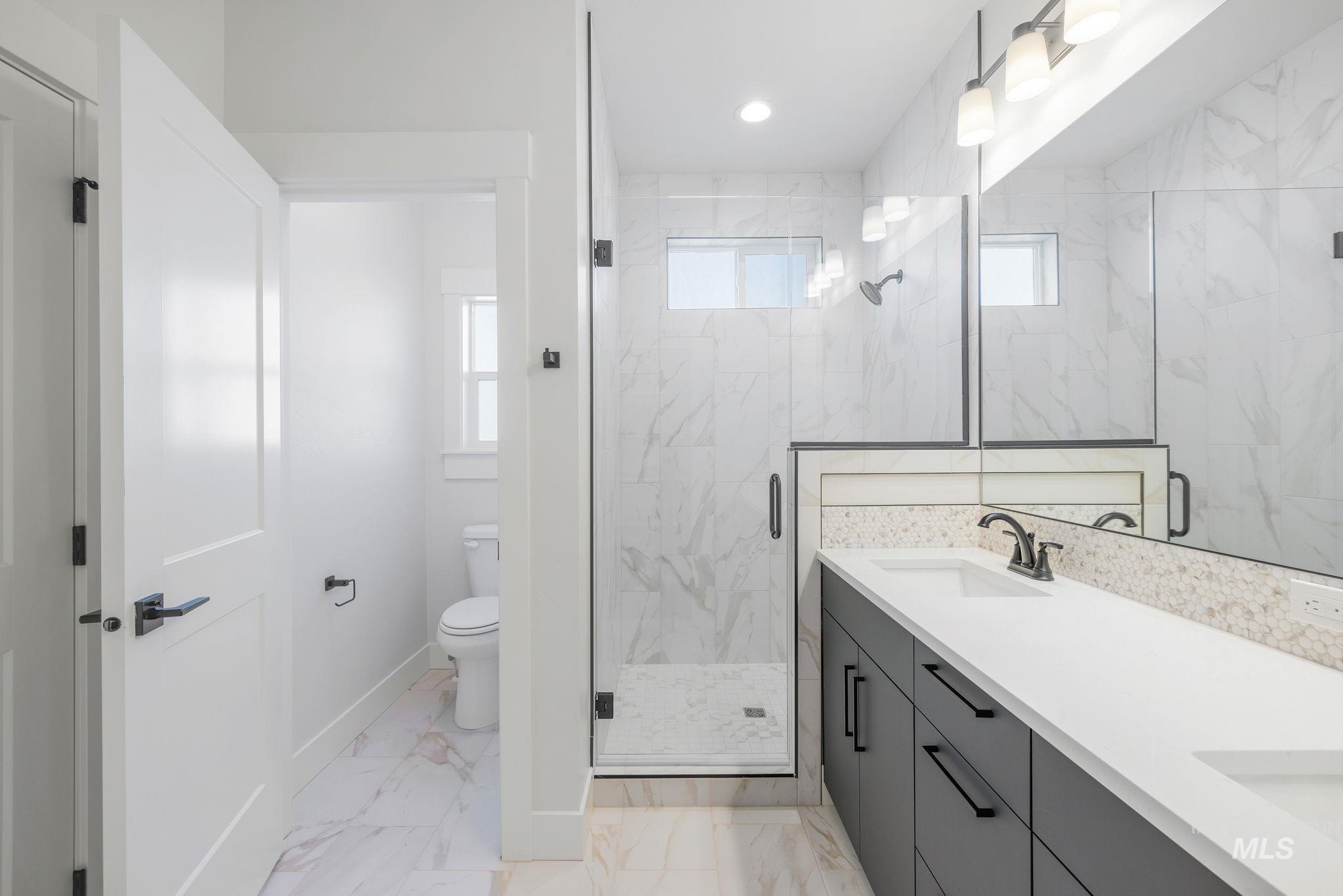 22 Bridger Street Cascade, ID 83611 - Photo 23 of 39 Bathroom featuring light marble finish floors, a marble finish shower, double vanity, and recessed lighting