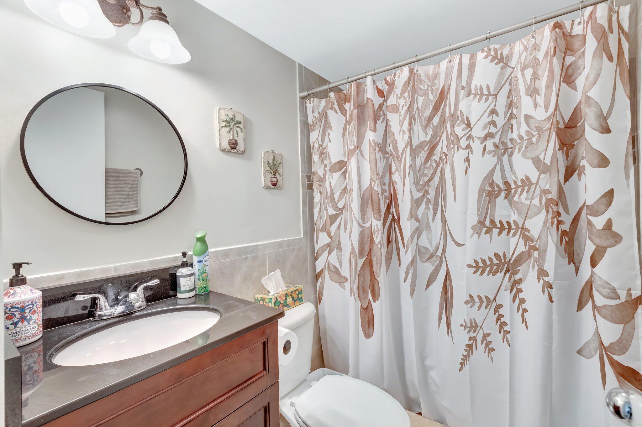 5260 Northwest 2nd Avenue, Unit 307 Boca Raton, FL 33487 - Photo 13 of 16 a bathroom with a granite countertop bathtub sink vanity mirror and a toilet