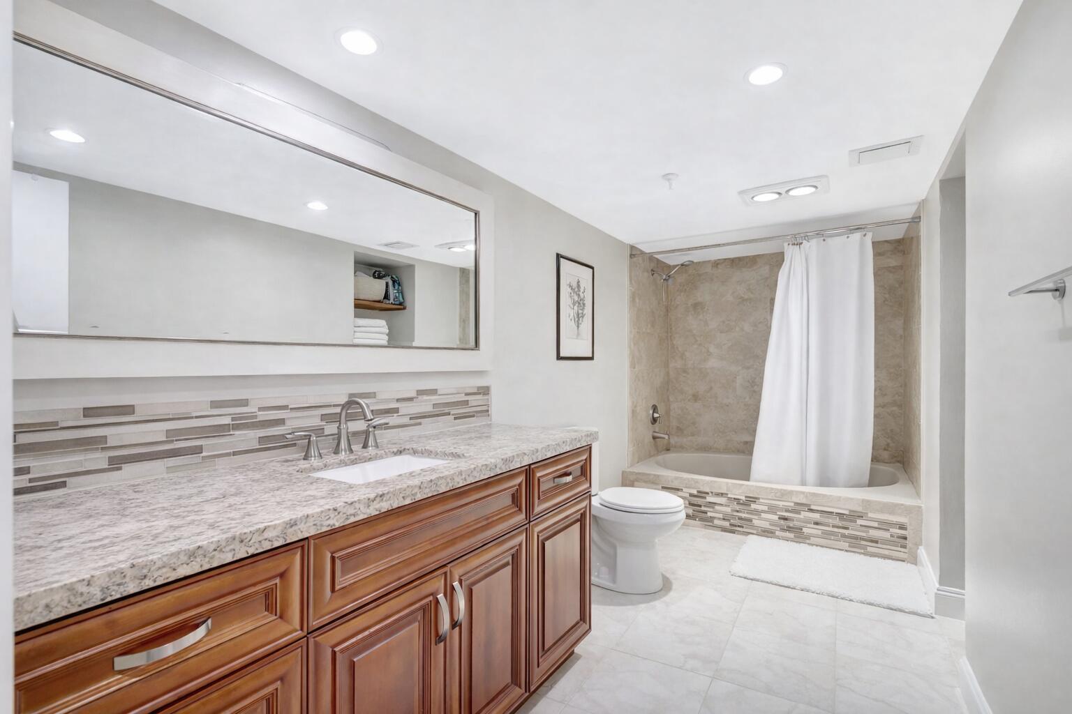 5260 Northwest 2nd Avenue, Unit 307 Boca Raton, FL 33487 - Photo 10 of 16 a spacious bathroom with a granite countertop sink a toilet a mirror and a bathtub