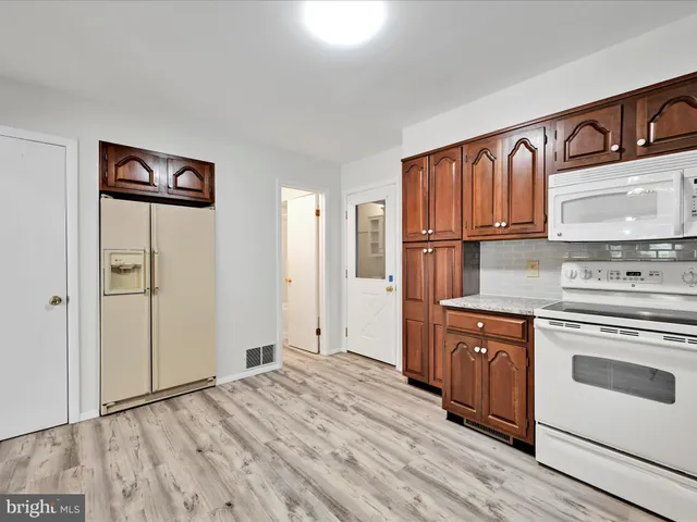 a large kitchen with stainless steel appliances granite countertop a stove a sink dishwasher and wooden cabinets with wooden floor