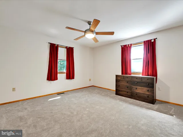 an empty room with windows and ceiling fan