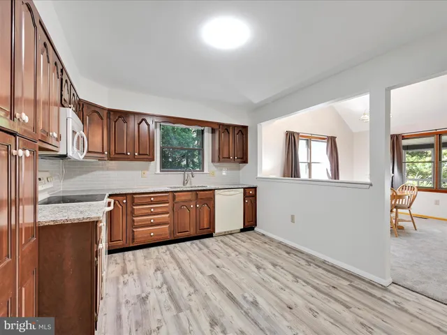 a kitchen with stainless steel appliances granite countertop a stove a sink dishwasher and a microwave oven with wooden cabinets