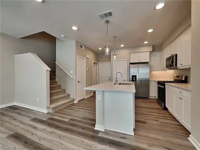 a kitchen with stainless steel appliances kitchen island hardwood floor sink and stove