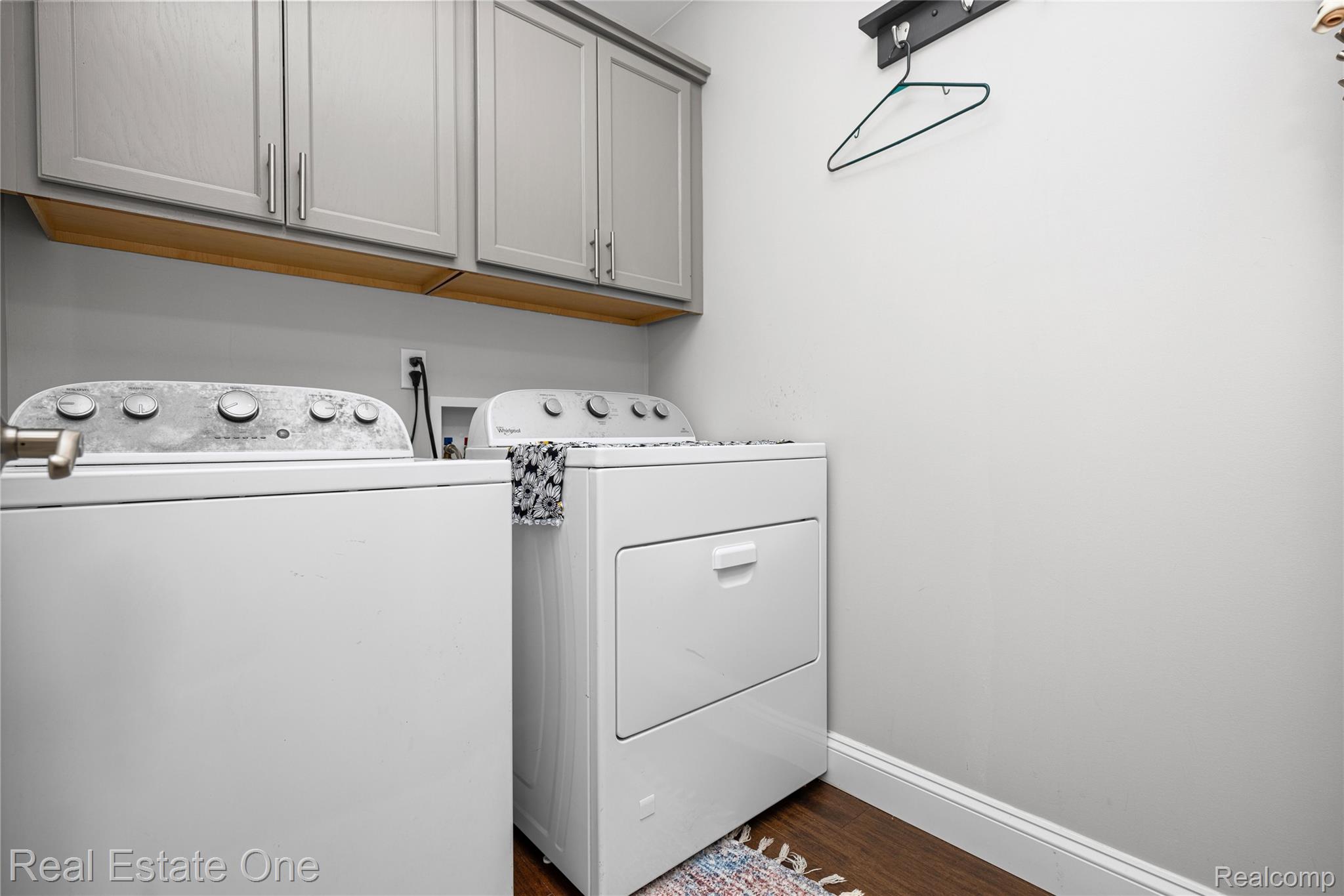 2479 Gibson Road Grand Blanc, MI 48439 - Photo 29 of 55 Dedicated laundry area featuring white washer and dryer units, overhead gray cabinetry with brushed nickel hardware, and wood-finish flooring