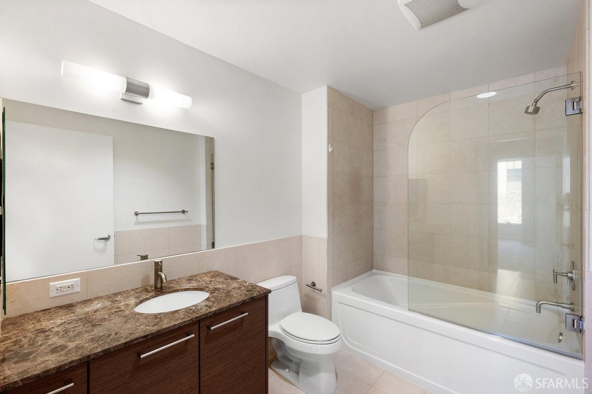 333 Main Street, Unit 4M San Francisco, CA 94105 - Photo 10 of 39 a bathroom with a granite countertop sink a toilet a mirror and bathtub