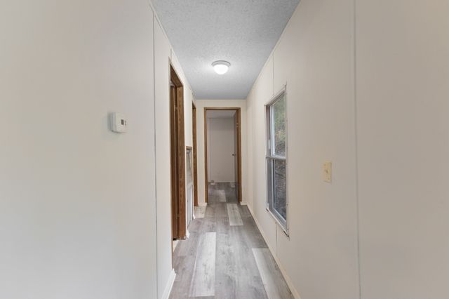 a view of a hallway with wooden floor and a bathroom