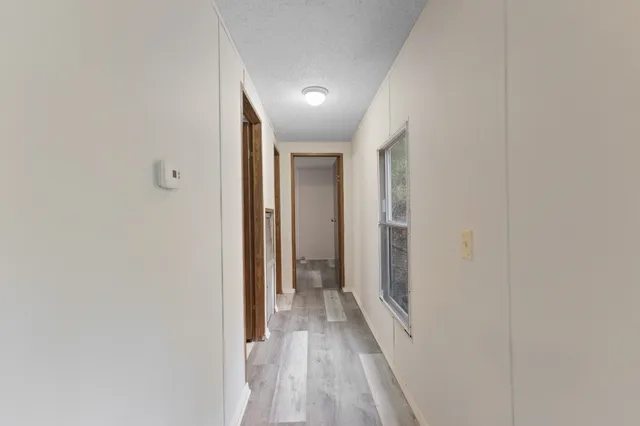 a view of a hallway with wooden floor and a bathroom