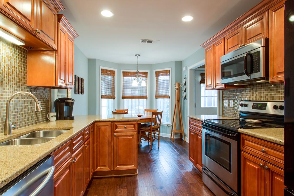 1323 General George Patton Road Nashville, TN 37221 - Photo 15 of 30 a kitchen with stainless steel appliances a stove sink microwave and cabinets