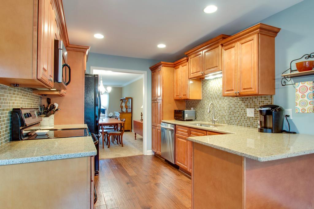 1323 General George Patton Road Nashville, TN 37221 - Photo 16 of 30 a kitchen with stainless steel appliances granite countertop a stove top oven a sink a dining table and chairs with wooden floor