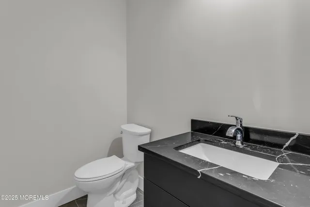 a bathroom with a granite countertop sink and a toilet