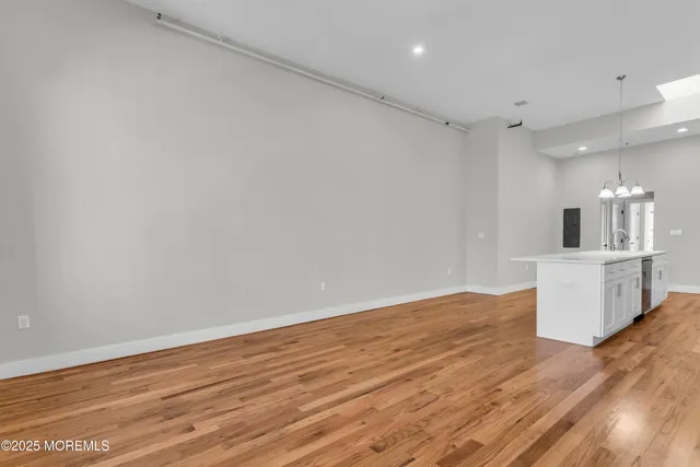 a view of kitchen and empty room with wooden floor