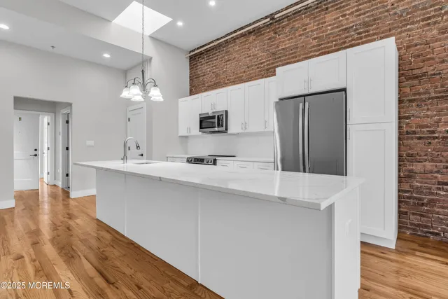 a large white kitchen with a sink and dishwasher a refrigerator with wooden floor