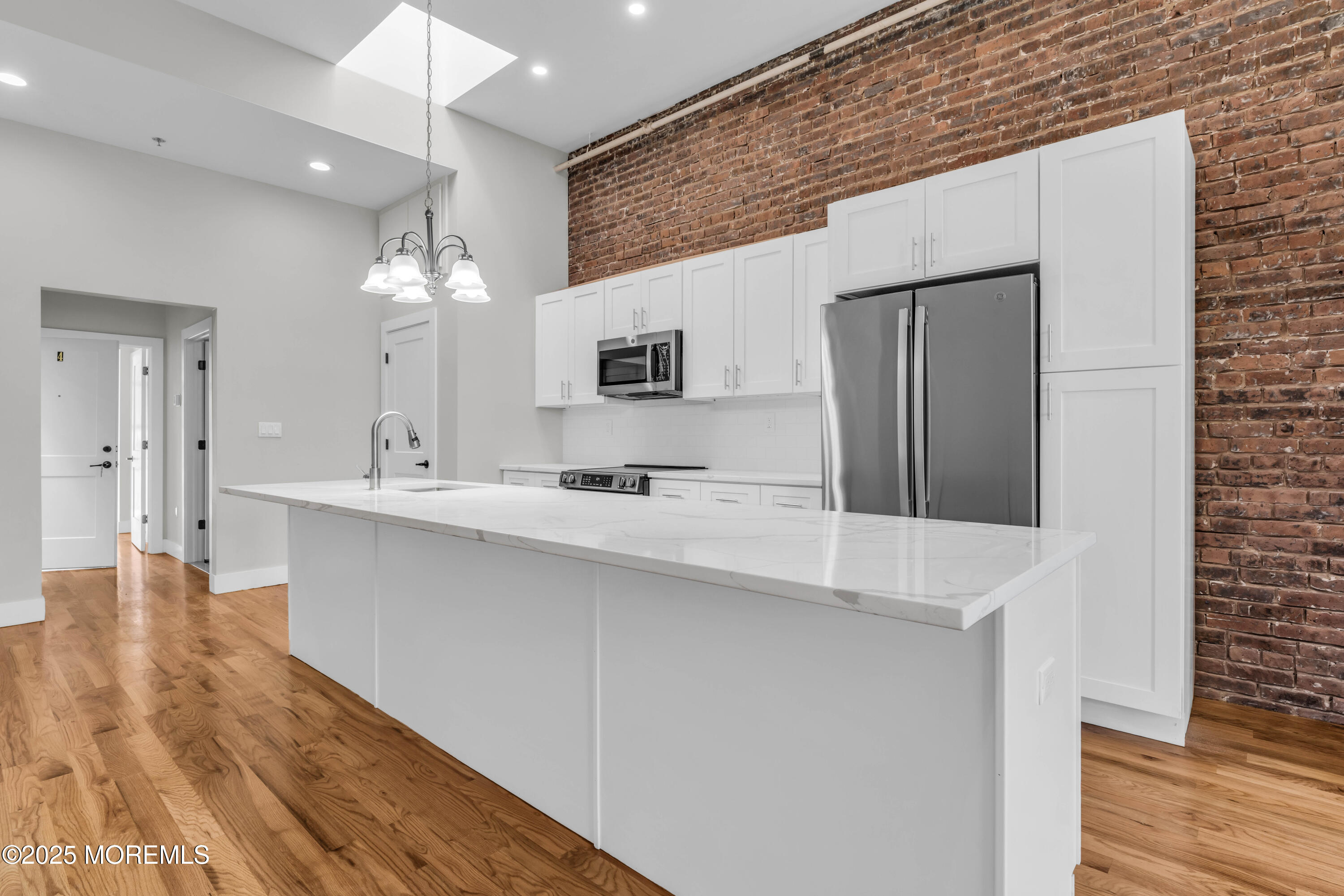7 Broad Street, Unit 4 Red Bank, NJ 07701 - Photo 7 of 23 a large white kitchen with a sink and dishwasher a refrigerator with wooden floor