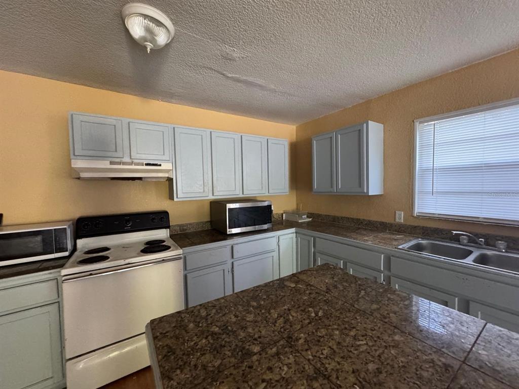 140 East 12th Street Apopka, FL 32703 - Photo 11 of 13 a kitchen with granite countertop a sink stainless steel appliances and cabinets