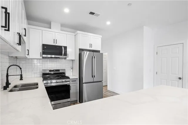 a kitchen with stainless steel appliances a refrigerator sink and white cabinets
