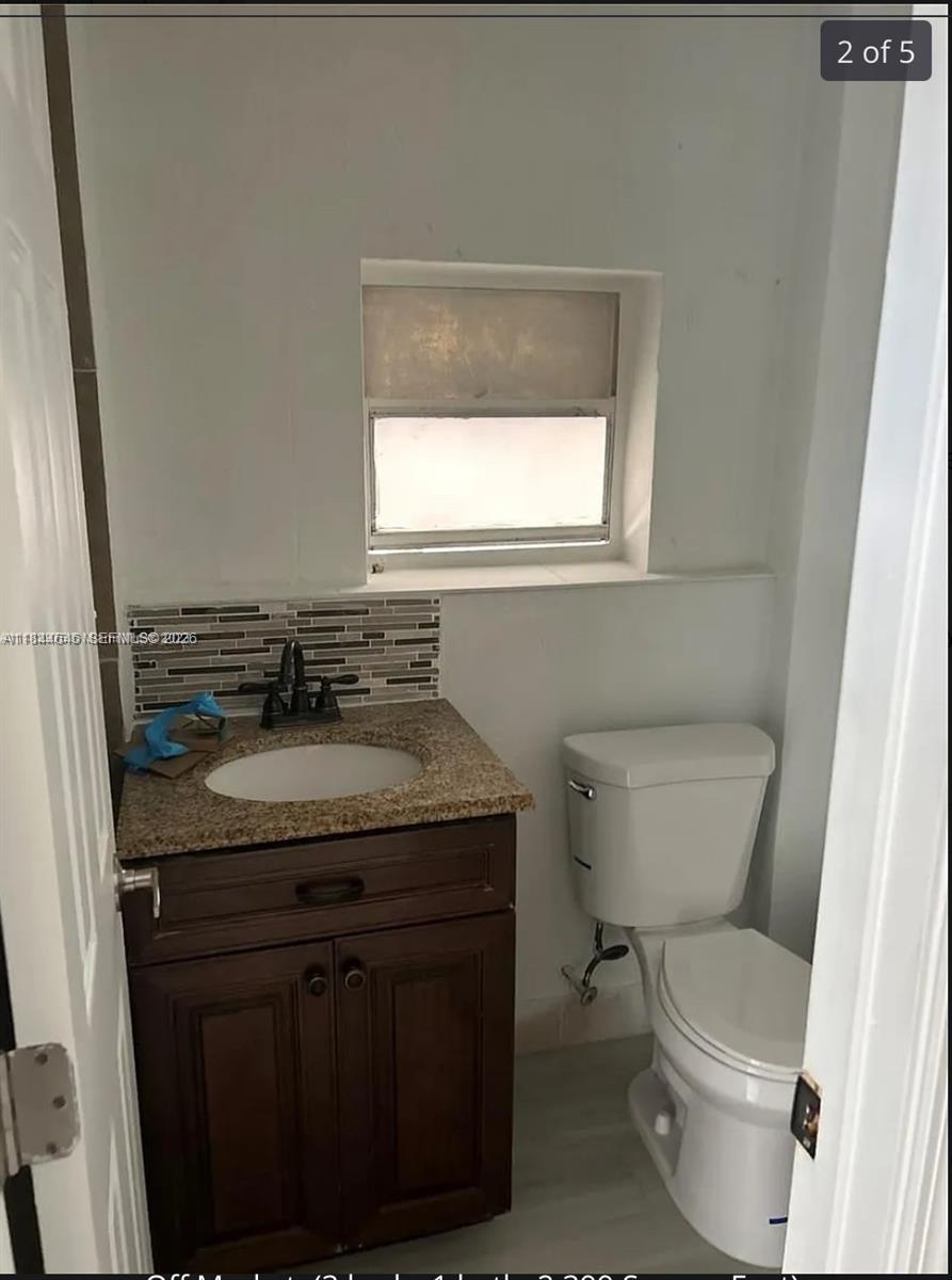 2215 Northwest 33rd Street Miami, FL 33142 - Photo 6 of 19 a bathroom with a granite countertop toilet a sink and a window