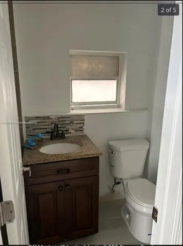 a bathroom with a granite countertop toilet a sink and a window
