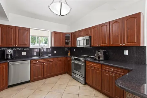 a kitchen with stainless steel appliances granite countertop wooden cabinets a stove top oven a sink and dishwasher
