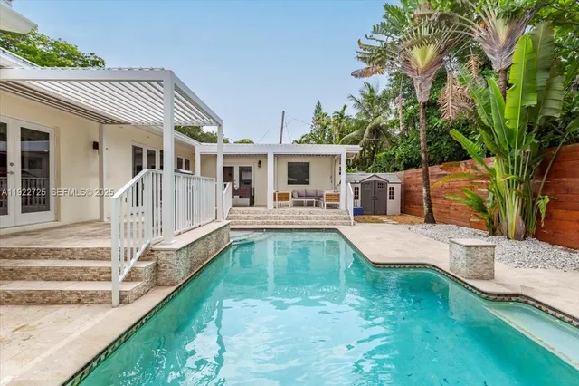 a view of a patio with table and chairs under an umbrella with a small yard