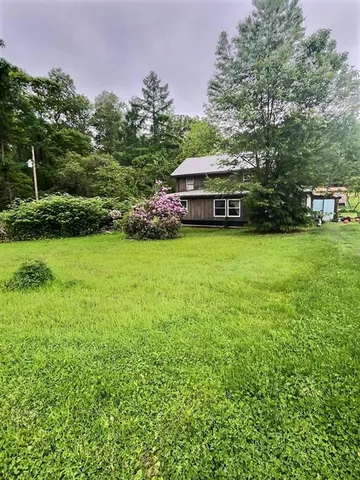 a yellow and red house sitting in the middle of a yard