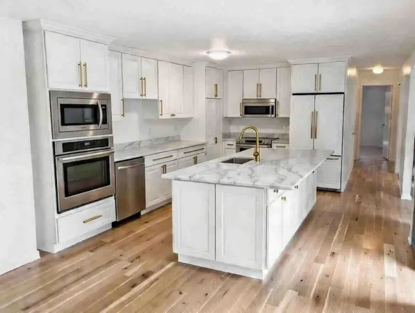 a kitchen with stainless steel appliances granite countertop a sink stove microwave and refrigerator