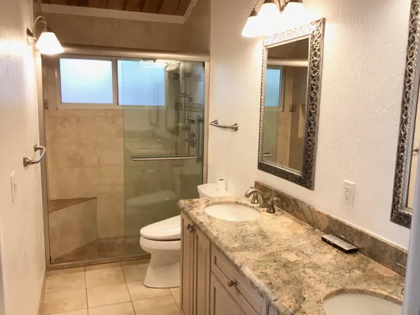 a bathroom with a granite countertop sink toilet and shower