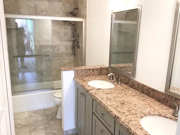 a bathroom with a granite countertop sink toilet and shower