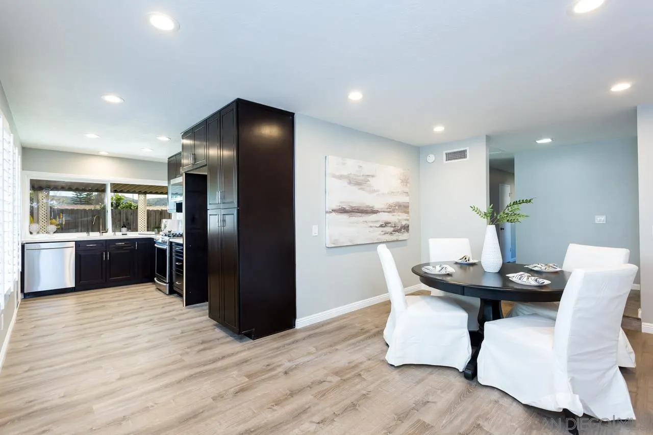 14427 Mirando Street Poway, CA 92064 - Photo 4 of 33 a kitchen with stainless steel appliances kitchen island granite countertop a refrigerator a sink a stove a dining table and chairs