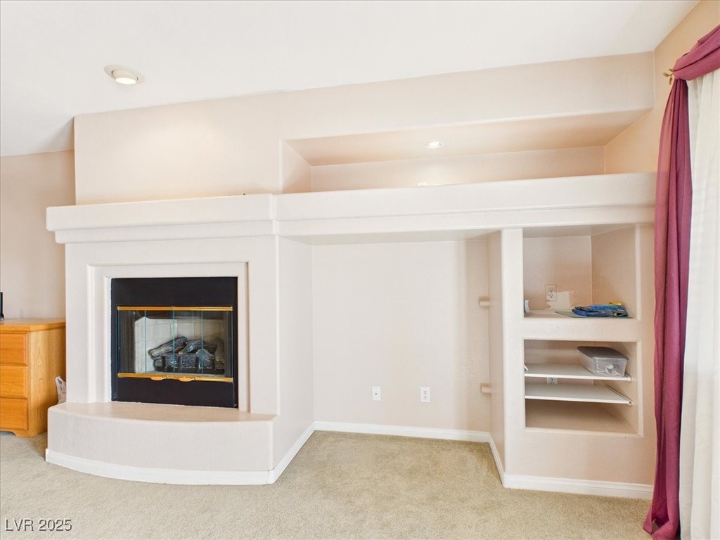 321 Whispering Tree Avenue Las Vegas, NV 89183 - Photo 45 of 95 Detailed view of a glass covered fireplace, carpet flooring, and built in shelves