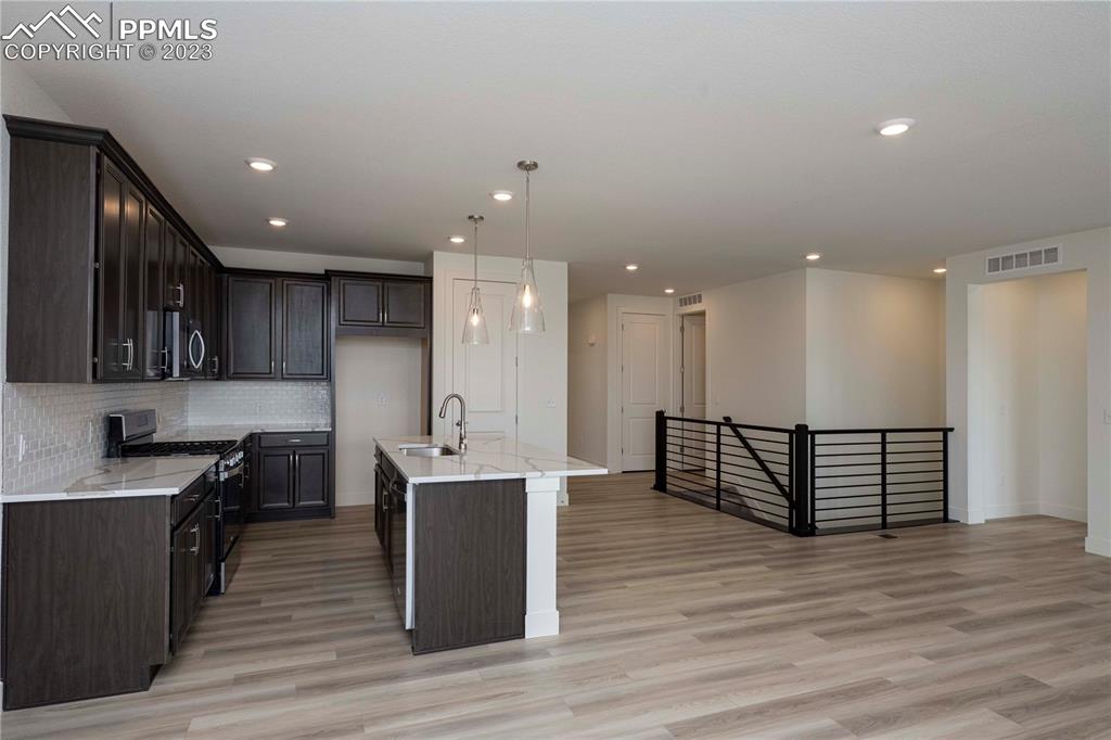 2042 Peachleaf Loop Castle Rock, CO 80108 - Photo 9 of 26 a kitchen with stainless steel appliances granite countertop a stove top oven a sink dishwasher and a refrigerator with wooden floor