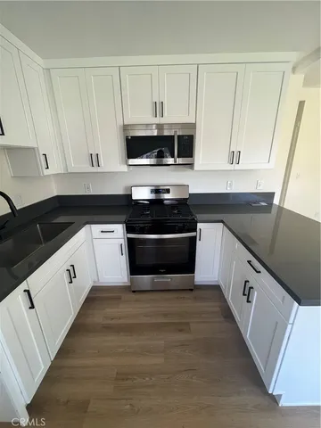 a white kitchen with sink and stainless steel appliances