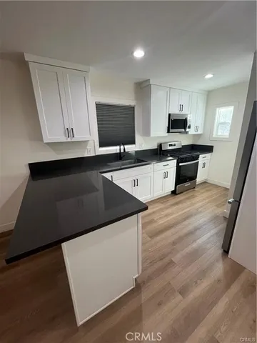 an empty room with wooden floor closet and windows