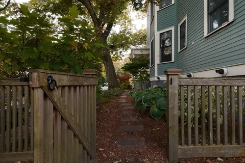 a view of a pathway of a house with wooden fence
