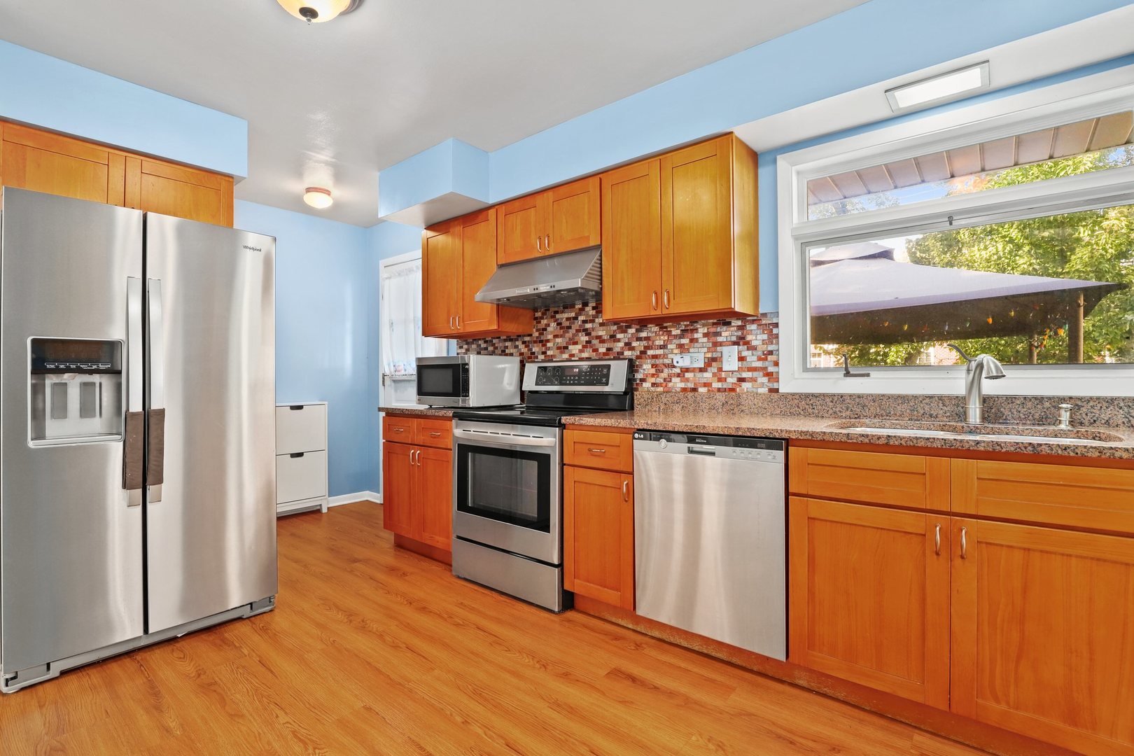 410 Ferndale Road Glenview, IL 60025 - Photo 8 of 34 a kitchen with stainless steel appliances granite countertop a refrigerator a sink dishwasher a stove and white countertops with wooden floor