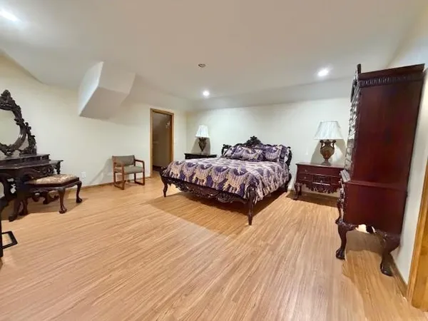 a bedroom with a bed a dresser and wooden floor
