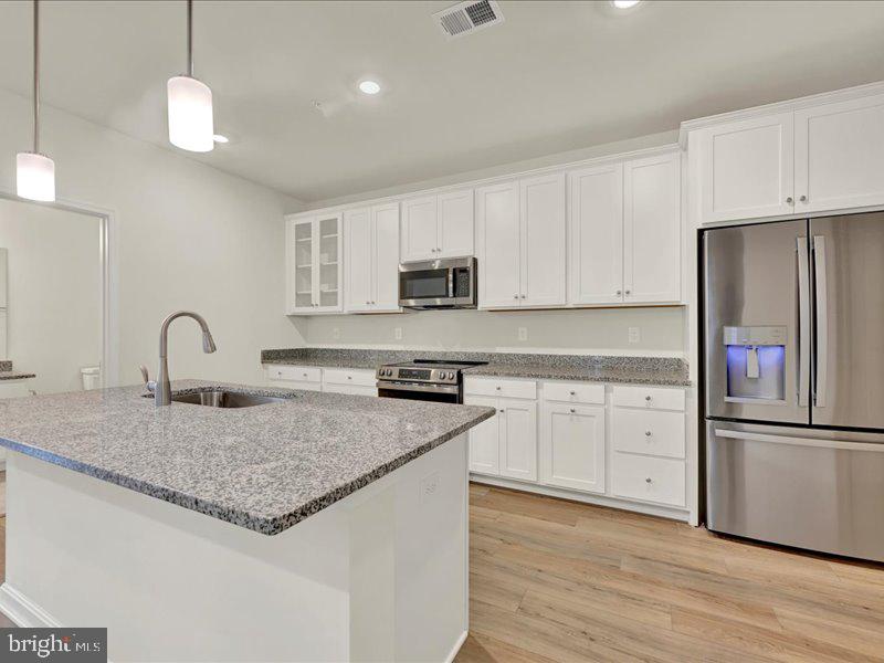 a kitchen with granite countertop white cabinets and stainless steel appliances